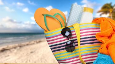 a beach bag filled with sandals and sunglasses and sunscreen and towels.