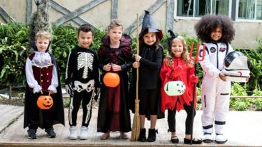 kids dressed in Halloween costumes standing on a street 