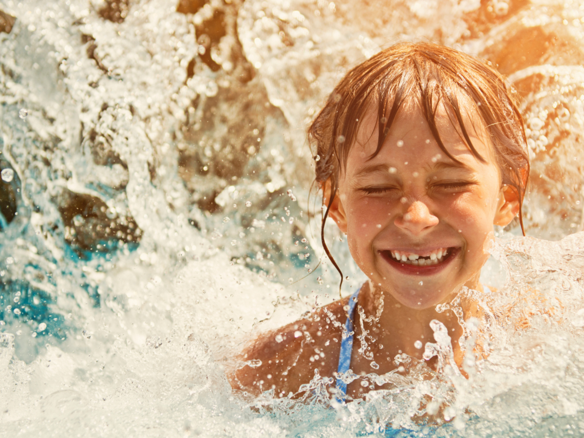 child in a pool with water splashing around her