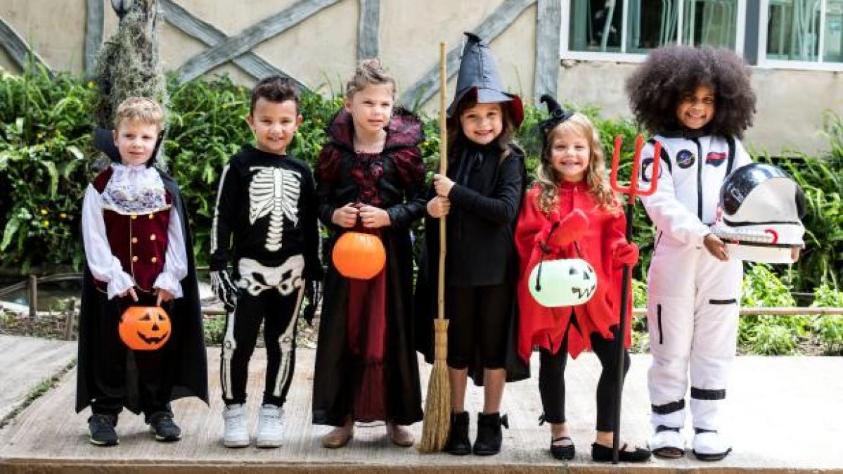 kids dressed in Halloween costumes standing on a street 