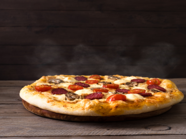 a round pizza with meat and cheese on top of a table