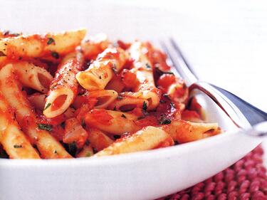pasta with red sauce in a bowl with a fork on the side