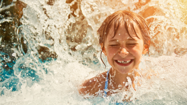 child in a pool with water splashing around her