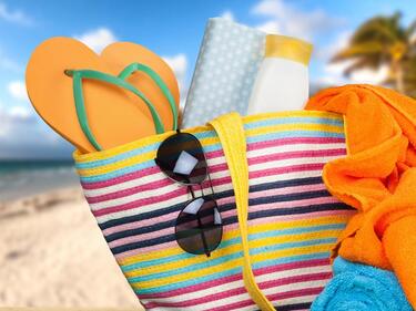 a beach bag filled with sandals and sunglasses and sunscreen and towels.