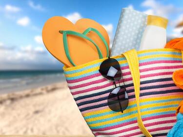a beach bag filled with sandals and sunglasses and sunscreen and towels.