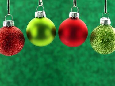 red and green Christmas bulb decorations hanging with a green background