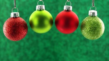 red and green Christmas bulb decorations hanging with a green background