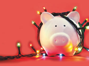 red background with a pig piggy bank wrapped in Christmas lights