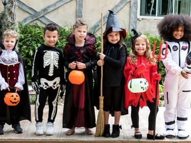 kids dressed in Halloween costumes standing on a street 