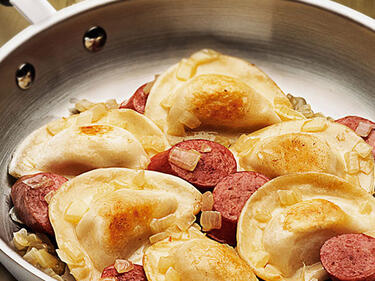 perogies and sausage in a frying pan