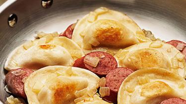 perogies and sausage in a frying pan